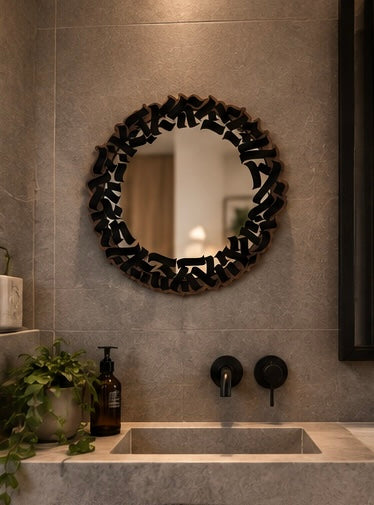Specchio decorativo MIRROR appeso a una parete chiara sopra una consolle in noce con vaso e decorazioni naturali.